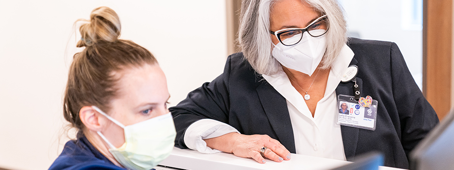 An OHSU RN works at a computer with the nursing director for her division.