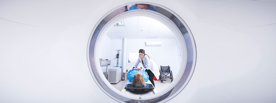 A doctor is helping a patient get comfortable before a radiation treatment. The patient is lying on a treatment bed. The doctor is leaning over them. The scene is framed by the circular opening of a radiation machine.