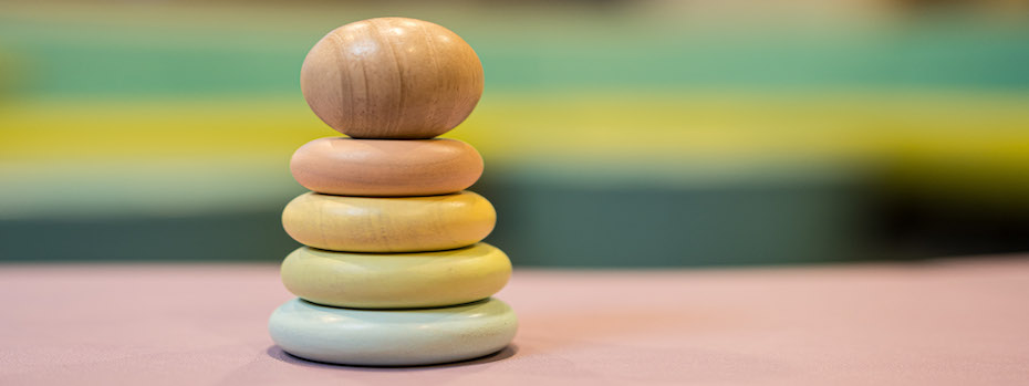 A wooden stacking toy made of rings and an egg.