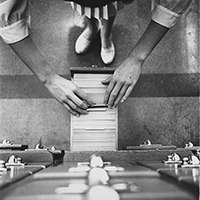 overhead view of two hands opening a drawer in an old-fashioned library card catalog