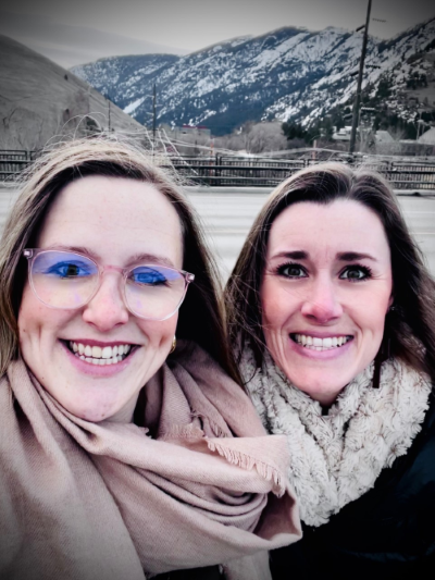 Jess and Jinnell take a selfie in front of mountains of Missoula, MT