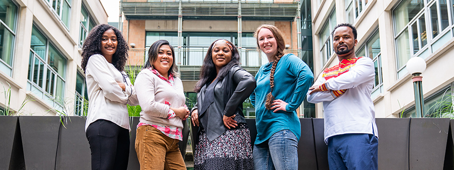 Five students standing tall and proud in front of an OHSU Portland campus building.
