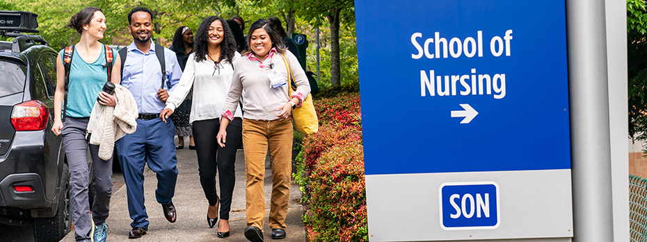 Four students laughing while walking past the OHSU School of Nursing sign.