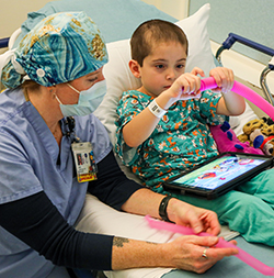 An OHSU child life therapist keeps a child company while he plays with a toy before spine surgery.