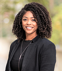 A portrait of a smiling Kat Phillips, in a black blazer.