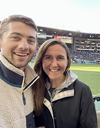 A man and a woman smiling while at a Portland Timbers game.