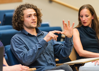 An OHSU Ph.D. student talks about his work with other students in an auditorium.