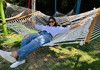 A woman smiling while laying on a hammock on a sunny day.
