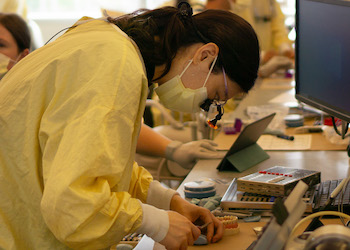 A dentistry student practices her skills on a dental model.