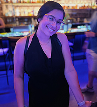 A woman smiling in front of a bar.