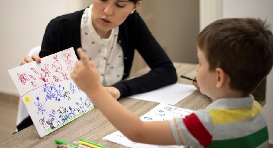 A child shows his drawing to an adult.