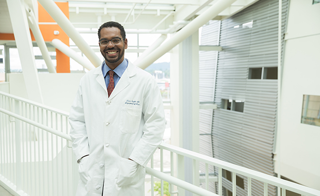 Dr. Donn Spight standing, hands in the pockets of his medical white coat, smiling while standing in an OHSU clinical building.