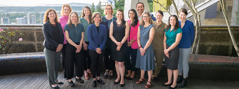 OHSU's Family Planning Program Team standing next to each other smiling in a courtyard with the OHSU Aerial Tram visible behind them.