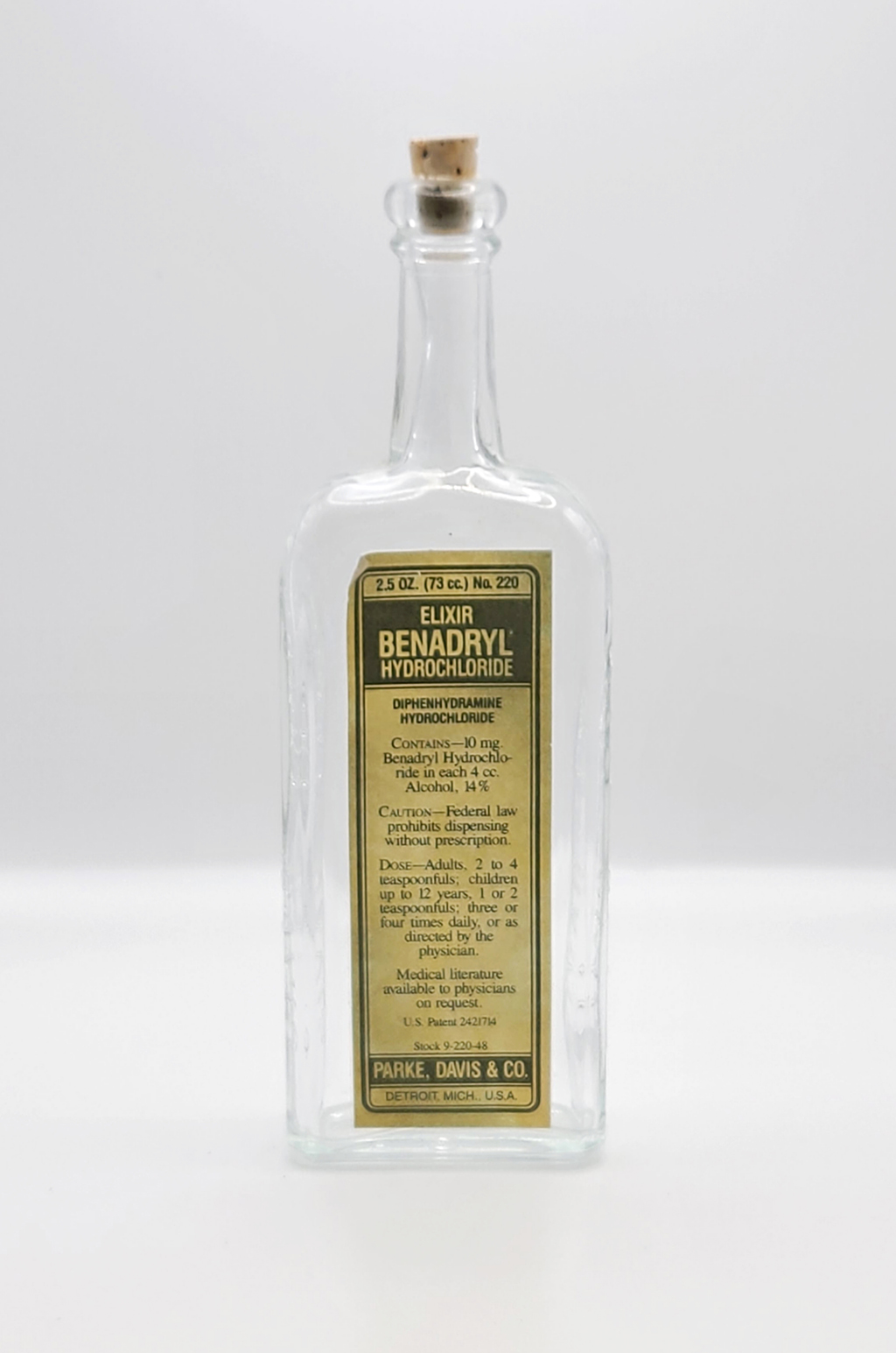 Clear bottle displays a yellow and green label, "Elixir Benadryl"