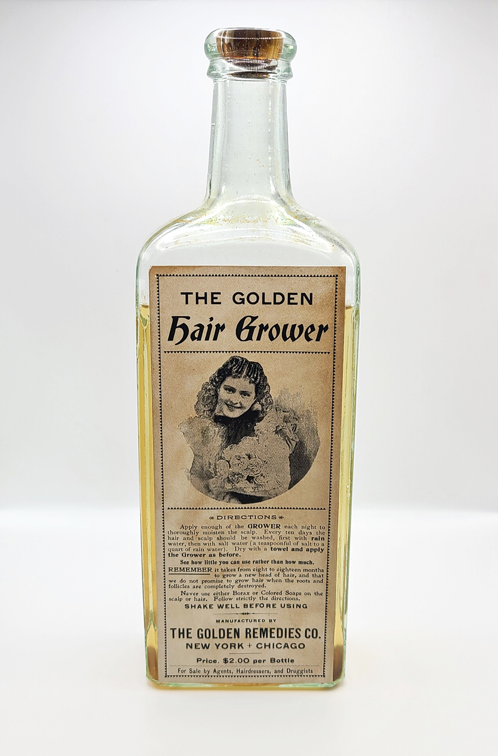 Clear bottle with a label "The Golden Hair Grower" which shows a smiling woman.