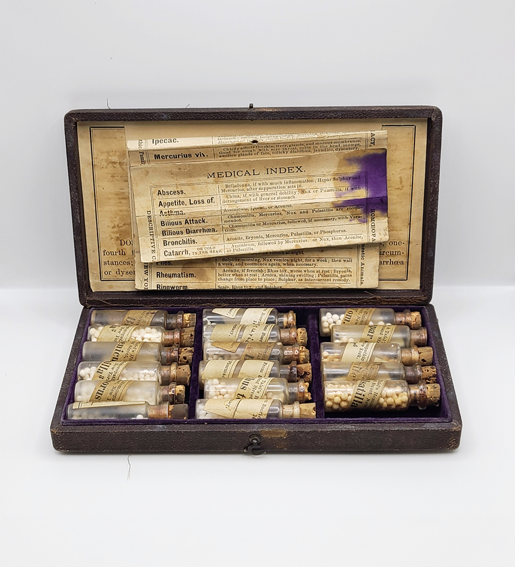 Open homeopathic medicine case contains many clear vials and bottles