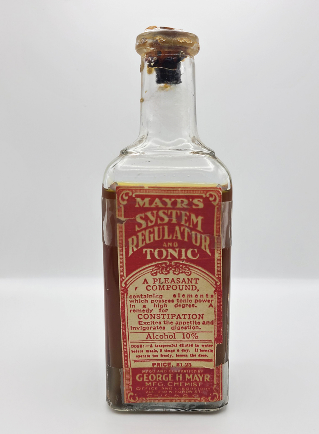 A bottle filled with brown liquid holds the label: "Mayr's System Regulator and Tonic"