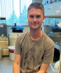 Noah Gladen-Kolarsky, seated in a lab, smiling