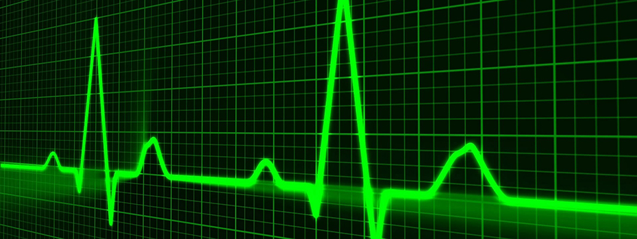 A glowing green line shows the peaks and valleys of a electronically traced pulse line against a back and green grid.
