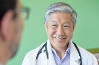 A doctor smiling as he speaks to a patient.