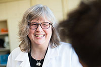 A woman smiling in a whitecoat as she speaks to a patient.