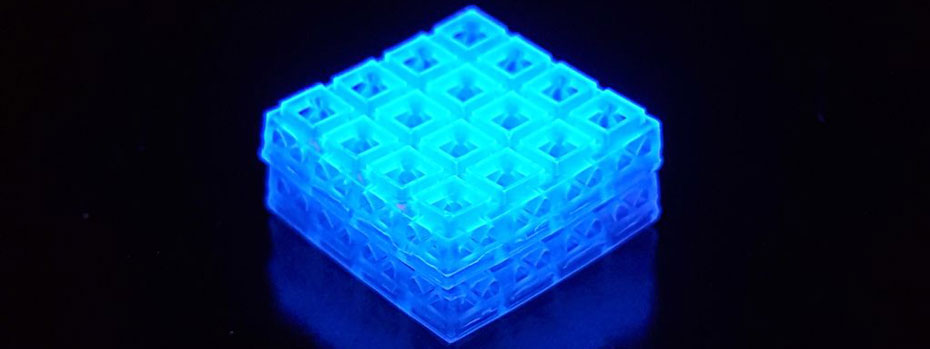 A cube composed of tiny bricks glows blue against a dark background.
