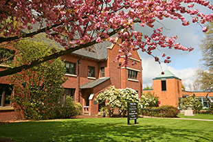 Monmouth campus on a spring day with a cherry blossom tree framing the brick building