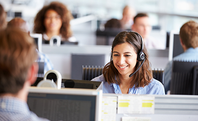 Young woman working in call centre, surrounded by colleagues