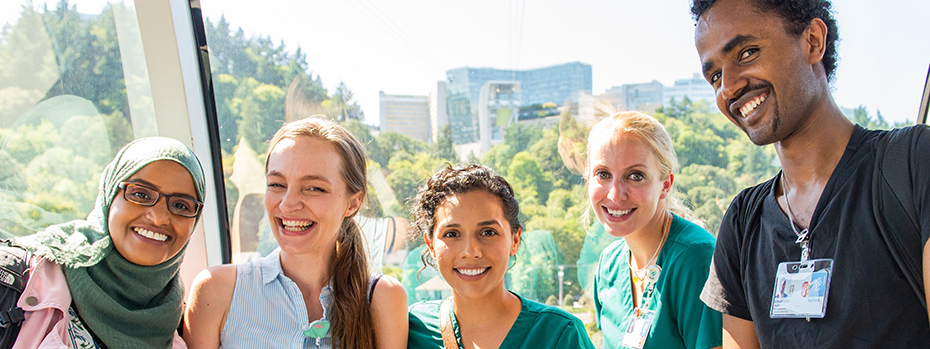Five nursing students stand in the Portland tram and smile at the camera. There is a mix of men and women.