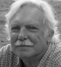 Headshot photo of Artist Michael Selker with light hair, mustache, and a plaid shirt.