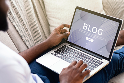 Picture of a person sitting on a couch reading a blog post on a laptop.