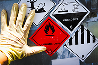 A gloved hand touching a wall with hazardous materials stickers.