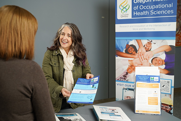 OccHealthSci exhibition table with people taking materials.