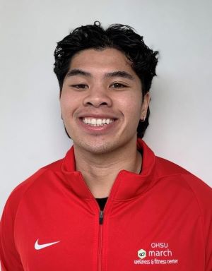 Headshot photo of Brandon Phanthavong, CPT, with dark hair, and red march wellness jacket