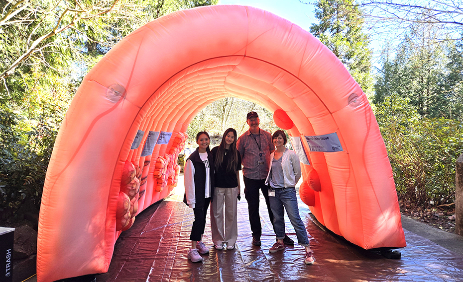 4 people stand under an 8-foot-tall inflatable colon 