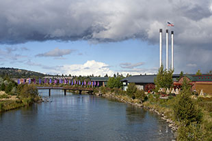 A landscape image of Bend, Oregon that includes the Deschutes River and the Old Mill's three towers.