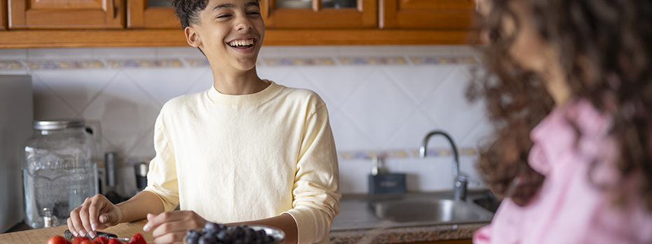 A child and his mother making food in a kitchen
