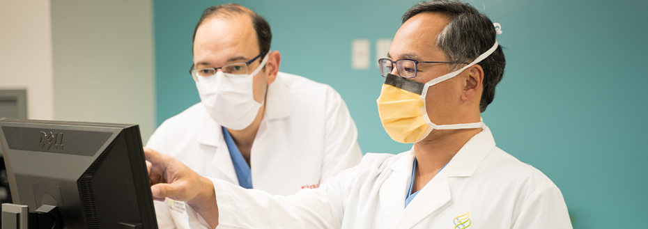 Dr. Zahr and Dr. Song wear masks and look at a computer monitor.