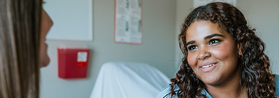 A teenage girl talks with her health care provider at the doctor’s office.