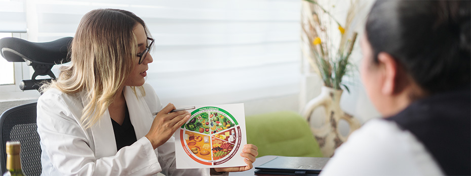 A registered dietitian shows a patient a diagram of a balanced plate during a nutrition consultation.