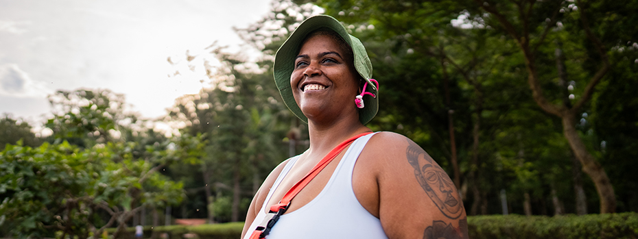 A woman smiles while standing outside on a cloudy day.