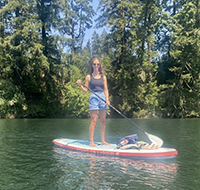A woman stand-up-paddleboarding on a sunny day.