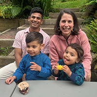 Beth Torwekar and her husband sitting at a table in a backyard with their two kids in front of them at the table eating.
