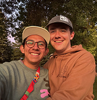 Two men taking a selfie outside with trees in the background.