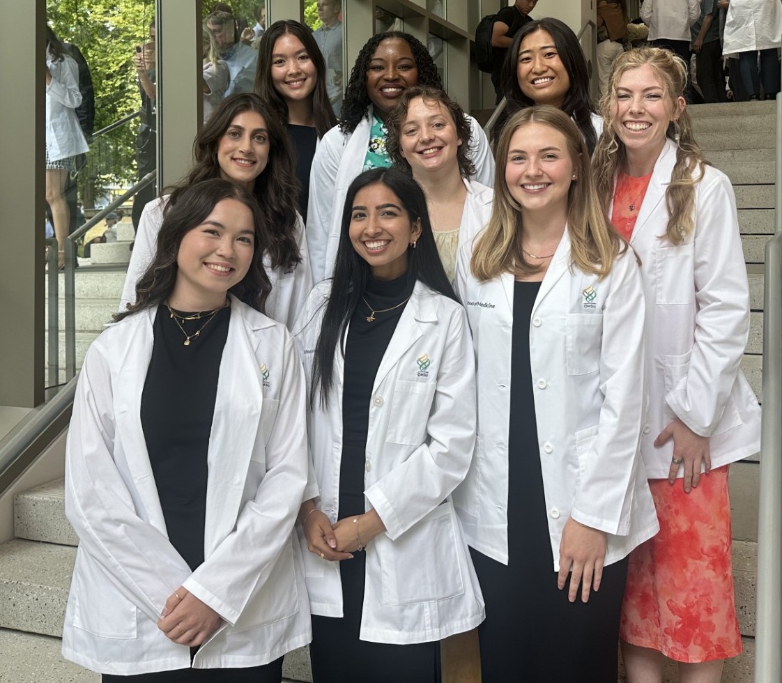 A group photo of nine MD-MPH students in their white coats