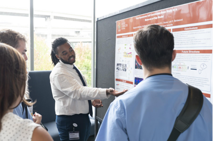 Intern Daquan Johnson stands beside his research poster 