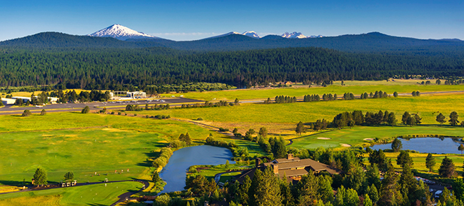 Aerial view of Sunriver Resort with lakes in foreground and mountains in the distance