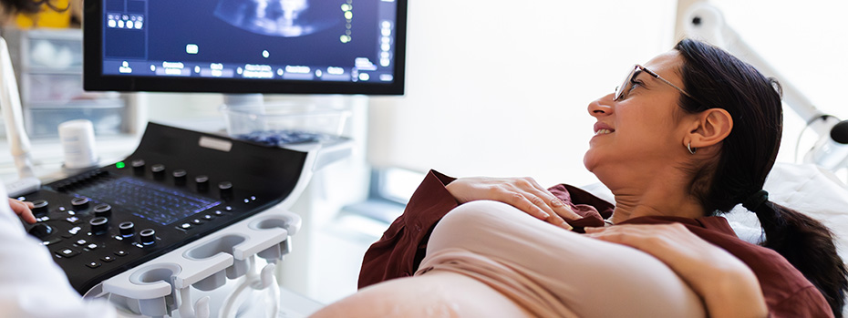 A pregnant woman looks at the monitor and smiles during an ultrasound exam.