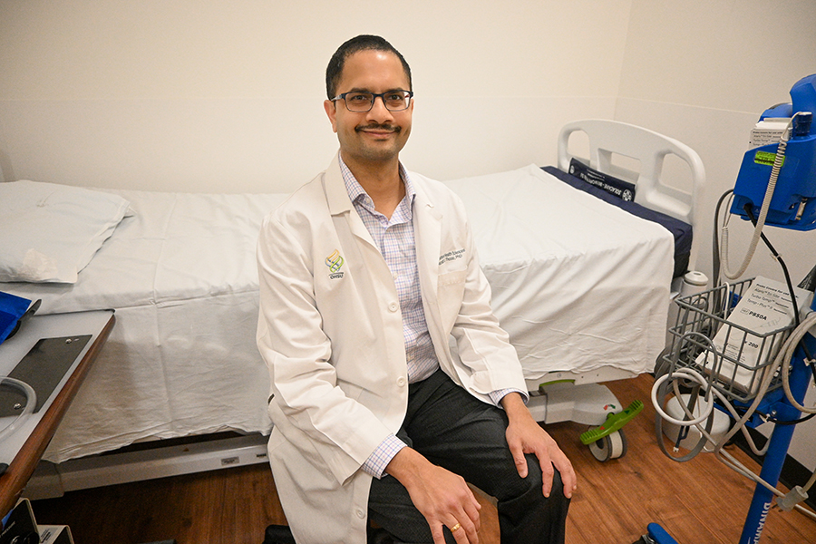Dr. Saurabh Thosar sitting in front of a hospital bed in an exam room wearing a white coat.