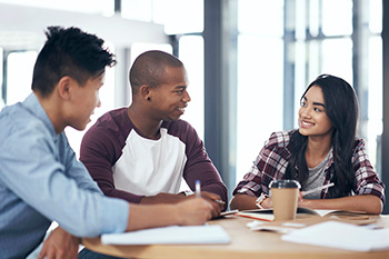 Three students studying together at a table in the OHSU library.